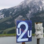 Das Kunstwerk ist Teil der Ausstellung „Weltbilder“ am Kunstwanderweg in Leogang. Die Ausstellung wurde von Anton Thuswaldner gemacht. Zu sehen ist eine Tafel mit einem Bild auf blauem Hintergrund. In der Mitte steht eine große Zahl 2, daneben die Buchstaben U2U. In roter Schrift steht das Wort moi. Daneben steht eine graue Steinskulptur. Im Hintergrund sieht man einen See und hohe Berge.